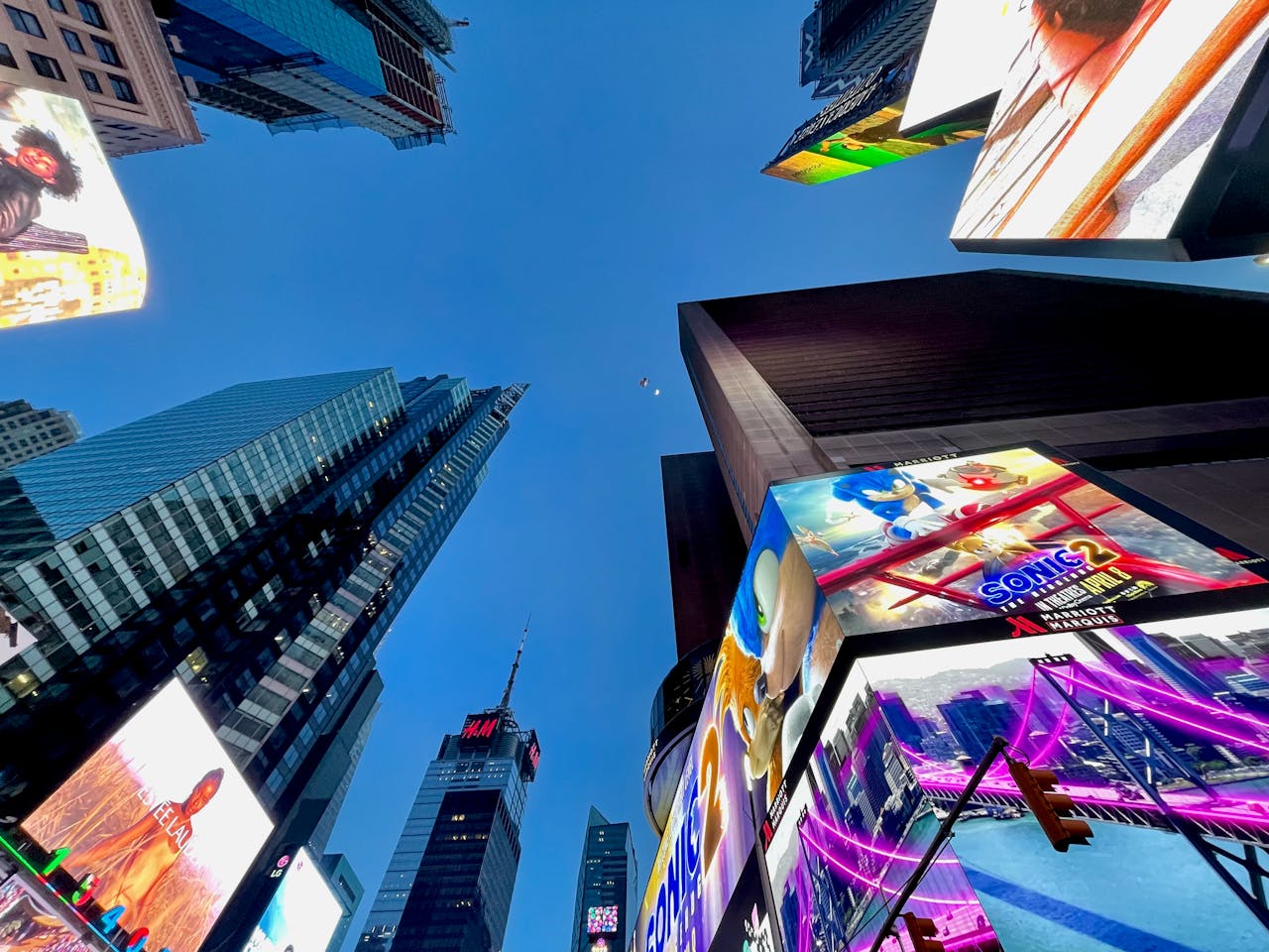 about-02 Low angle view of illuminated billboards and skyscrapers in Times Square, NYC at dusk.