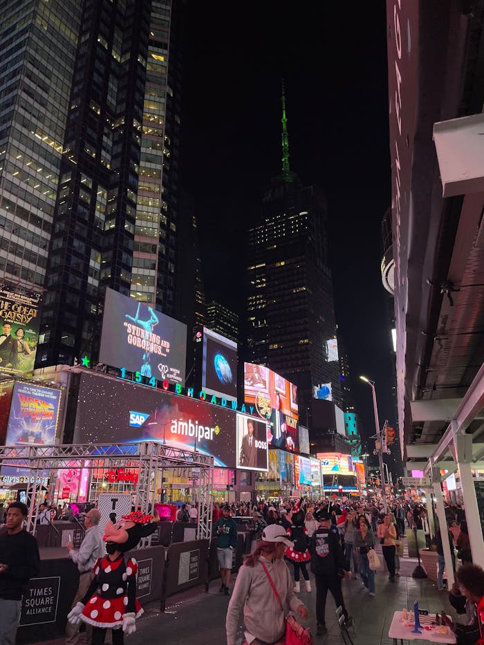 Bustling night scene at Times Square, New York City, with vibrant lights and crowds.