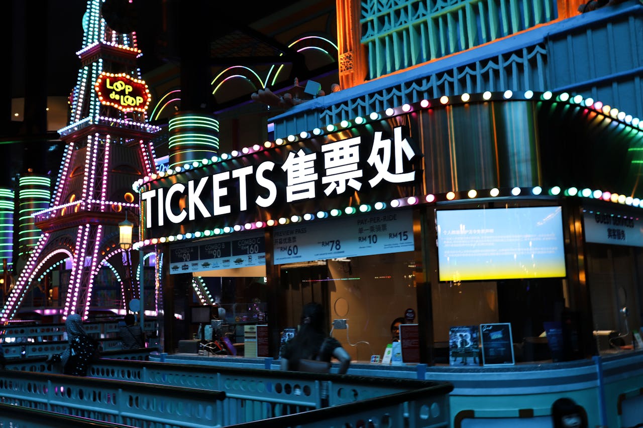 Illuminated ticket booth with vibrant neon lights at night, featuring colorful signage.