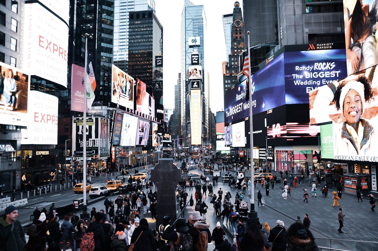 about-04 A bustling Times Square scene with bright billboards and numerous pedestrians in New York City.